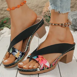 Close-up of bohemian floral print thong sandals with chunky heels on a white wooden floor