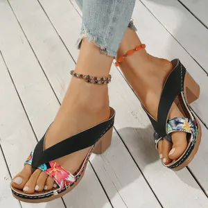 Ethnic floral print chunky heel flip-flop sandals shown on a model on a wooden deck