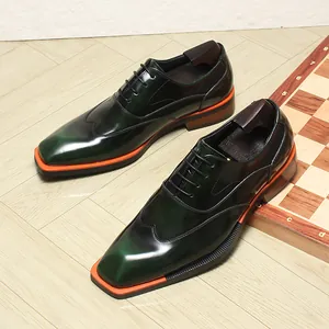 Detail of dark green glossy leather Oxford shoes with contrasting orange sole