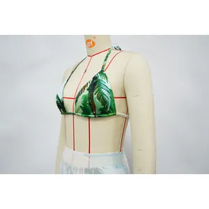 Close-up detail of green tropical leaf print bikini top shown on a white dress form