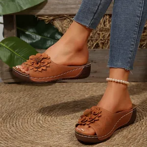 Vista detallada de cerca de sandalias con cuña marrones con flor y diseño calado