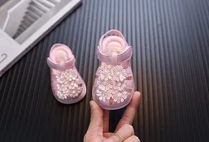 Detailansicht rosa Babysandalen für Mädchen mit eleganten Spitzenblumen und Perlen.