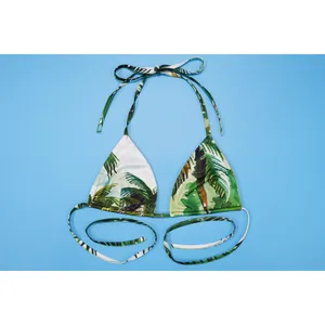 Detail view of bikini top with tropical palm tree print on vibrant blue background.