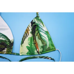 Close-up detail of sexy bikini top with green tropical palm leaf print and thin straps