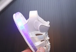 Nahaufnahme einer weißen Baby-Prinzessin-Sandale mit lilafarbenem LED-Leuchteffekt