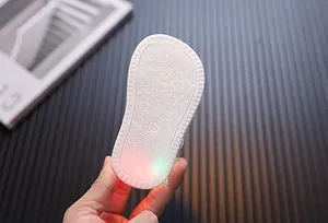 Nahaufnahme der weißen Gummisohle eines Lauflernschuhs mit leuchtendem LED-Licht