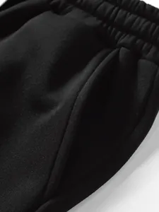 Close-up detail of the side pocket and elastic waistband on black fleece joggers.