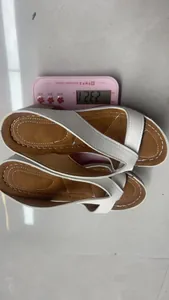 Detail view showing the weight of the white wedge thong sandals on a scale at 232.1g.