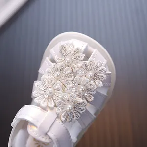 Nahaufnahme weißer Baby-Prinzessin-Sandalen mit Paillettenblumen und glänzenden Perlen
