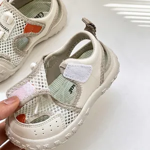Détail des sandales pour bébé en maille respirante avec bride velcro blanche et orange