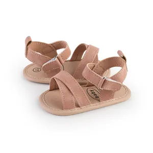 Close-up detail of pink soft suede baby sandals with cross straps and adjustable velcro