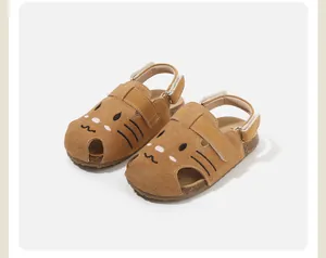 Detailed view of brown suede kids sandals featuring a cute cartoon cat face design.