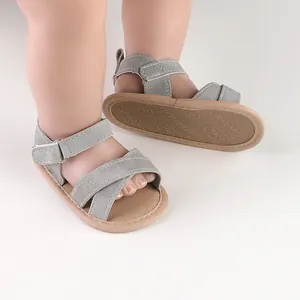 Close-up view of grey suede baby summer sandals featuring cross straps and adjustable velcro