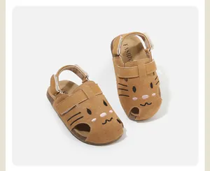 Close-up of brown suede baby sandals with cute cartoon cat face embroidery detail