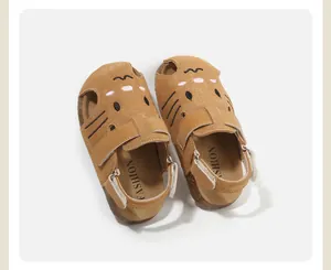 Detailed close-up of cartoon cat embroidery on brown suede toddler sandals with strap