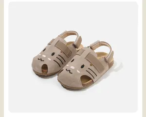 Close-up detail of children's khaki suede sandals featuring a cute cartoon cat face design.