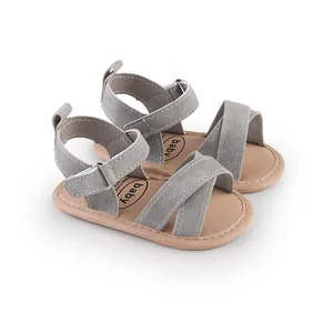 Detail view of gray suede baby sandals featuring cross-strap design and soft tan soles
