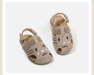 Detail view of the cute cartoon cat face embroidered on suede baby walking sandals.