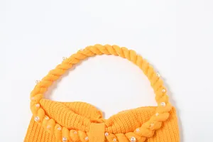 Dettaglio del top in maglia gialla con spalline americane a torchon e perline bianche.