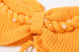 Dettaglio macro del set in maglia arancione con trama intrecciata e perle
