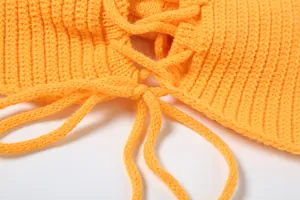 Dettaglio ravvicinato dell'allacciatura regolabile su un top in maglia a coste arancione
