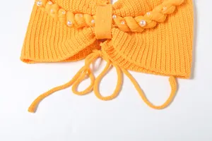 Dettaglio del top a fascia in maglia gialla con perle e design a treccia decorativa