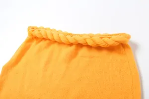 Dettaglio ravvicinato di tessuto a maglia arancione con decorazione a corda ritorta al bordo