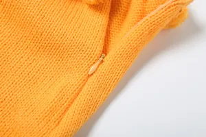 Primo piano della trama in maglia arancione brillante e dettaglio della zip invisibile