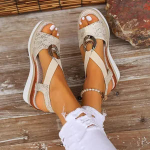 Close-up detail of women's stylish gold wedge sandals with elastic straps and ring