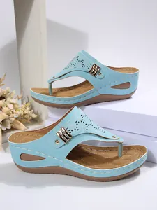 Detail view of light blue summer wedge sandals featuring laser-cut motifs and gold buckle.
