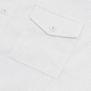 Primo piano della tasca di una camicia di velluto bianco con trama e bottone.