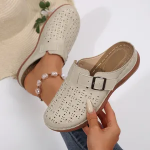Gros plan de mules à plateforme beige perforées avec bride à boucle et motifs fleuris