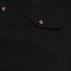 Dettaglio macro di una camicia da uomo in velluto nero, trama di tasca e bottone.