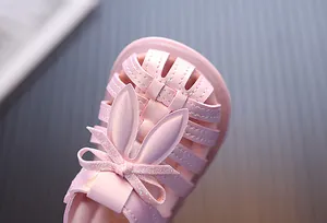 Detailansicht von rosa Kleinkindsandalen mit süßen Hasenohren und Glitzerschleife.