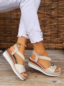 Close-up of stylish women's wedge sandals with round buckle and textured straps