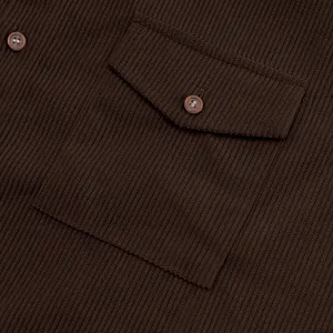 Primo piano della tasca di una camicia di velluto a coste marrone con bottone coordinato