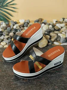 Detalle de sandalias de cuña para mujer con correas cruzadas negras y acentos dorados