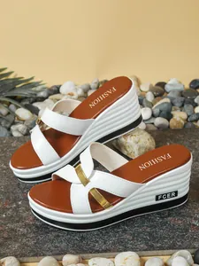 Primer plano de sandalias de cuña blancas con hebillas doradas y plantillas marrones