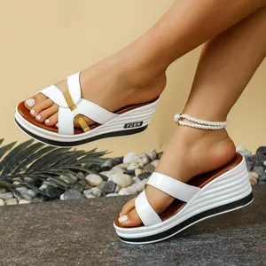 Primer plano de sandalias de cuña blancas con plataforma y detalles en oro