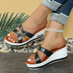 Detalle de elegantes sandalias negras de cuña para mujer con plataforma blanca y oro.