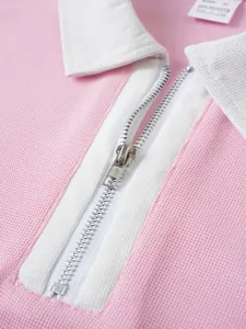 Detaillierte Makroansicht des hochwertigen silbernen Reißverschlusses am rosa Herren-Poloshirt