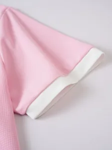 Nahaufnahme des rosa Netzgewebes und der weißen Rippbündchen an einem Herren-Polo