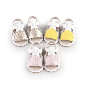 Detail shot of baby summer walking sandals in pink, yellow and gold shell designs.
