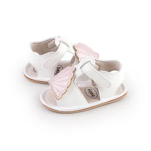 Detailed macro shot of white infant walking sandals featuring pink wing applique design