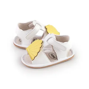Macro detail view of white baby summer walking sandals featuring yellow wing embellishment