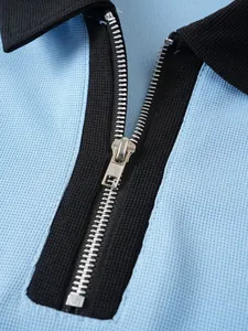 Detailaufnahme eines Metallreißverschlusses und blauen Strukturgewebes eines Poloshirts