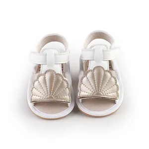 Detailed front view of white baby sandals with gold shell accent for pre-walkers.