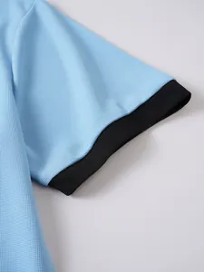 Nahaufnahme von hellblauem Netzgewebe mit einem schwarzen Rippbündchen am Ärmel eines Polohemds