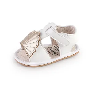 Detailed view of white baby summer sandals featuring a decorative golden shell appliqué