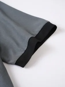 Nahaufnahme von Polohemdärmel mit grauem Strukturstoff und schwarzem Rippbündchen